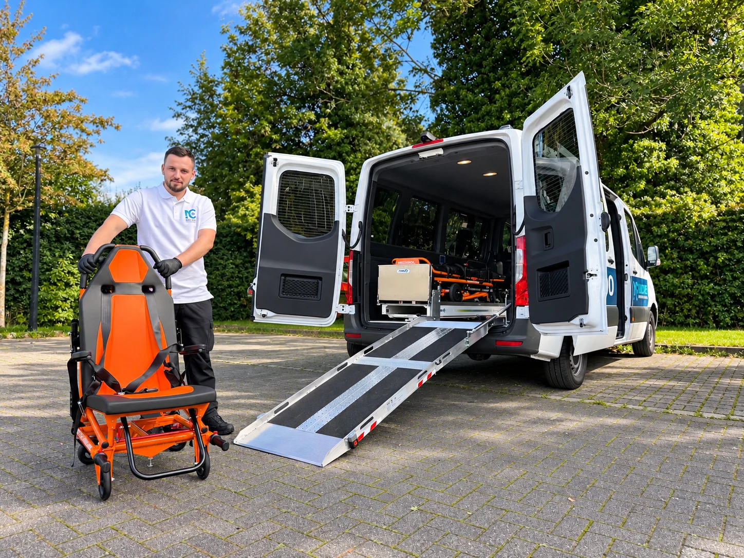 Mitarbeiter mit orangefarbenem Tragestuhl vor dem Sprinter mit ausgeklappter Rampe