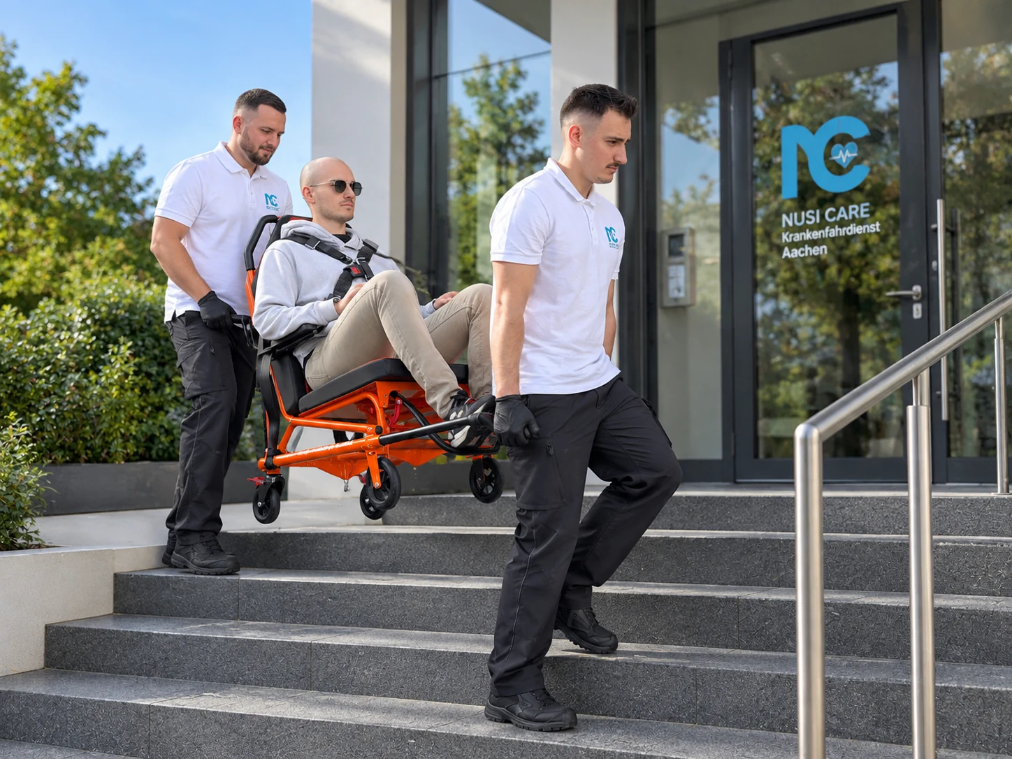 KI-generiertes Symbolbild: Zwei Mitarbeiter tragen eine Person im Tragestuhl eine Außentreppe hinunter