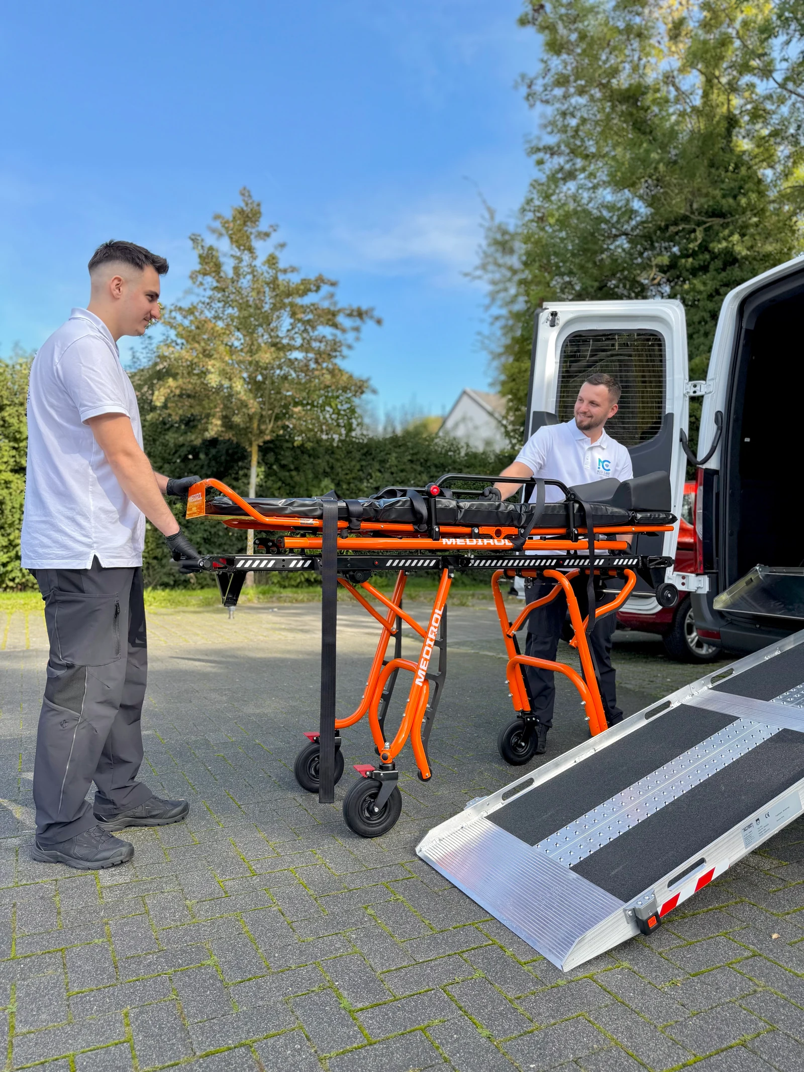 Zwei Nusi Care Mitarbeiter mit einer leeren Transportliege am Sprinter